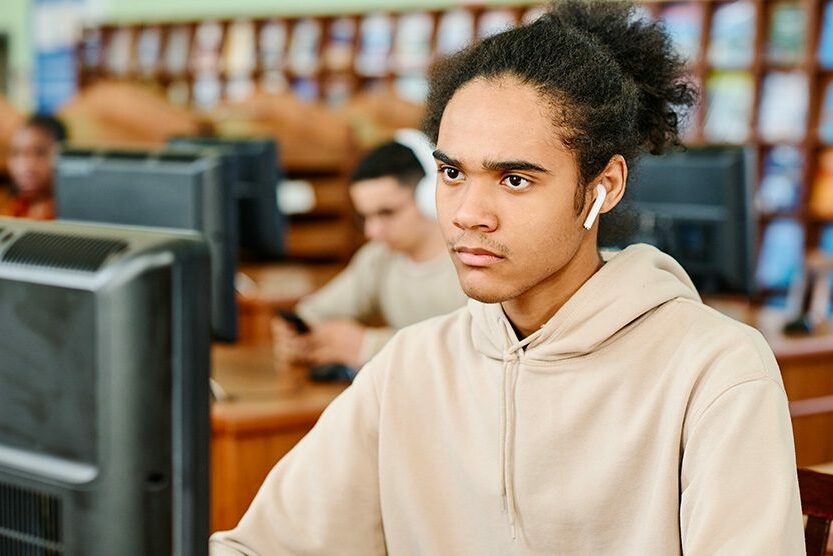 Jeune homme travaillant devant un ordinateur dans une bibliothèque